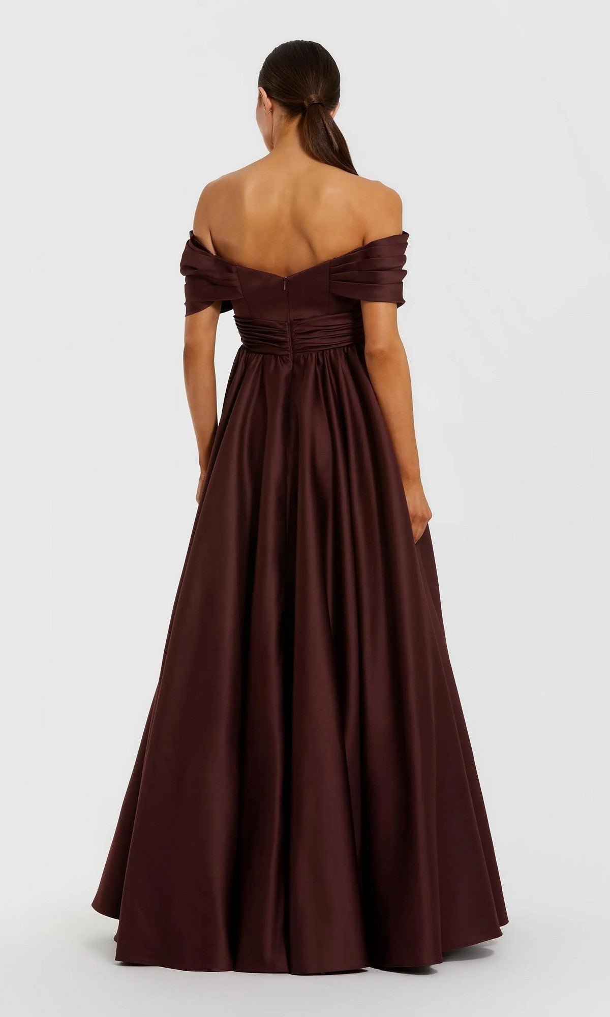 A woman with her hair in a low ponytail faces away, wearing the Mac Duggal 56188 Long Formal Dress—an off-the-shoulder, floor-length dark burgundy satin gown with a fitted bodice and flared skirt. Plain white background.